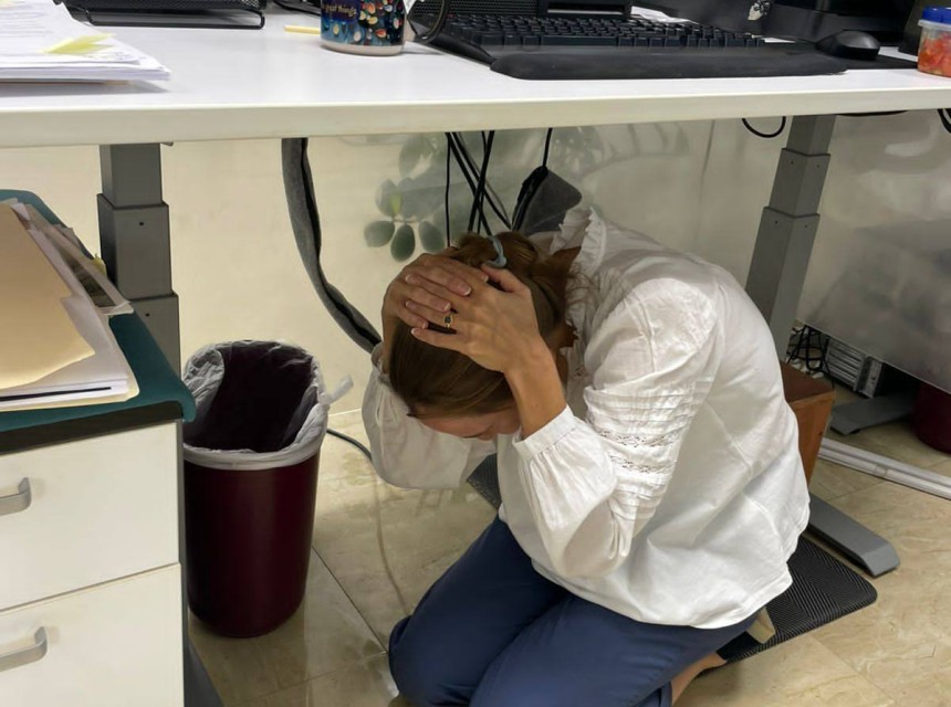 A Governor's Office staff member carries out the drop, cover and hold safety technique in the October 16 ShakeOut exercise